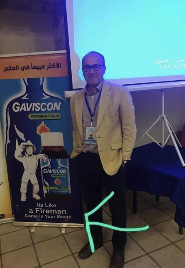 Man standing next to a confusing English translation on a Gaviscon poster showing a fireman and product bottle.