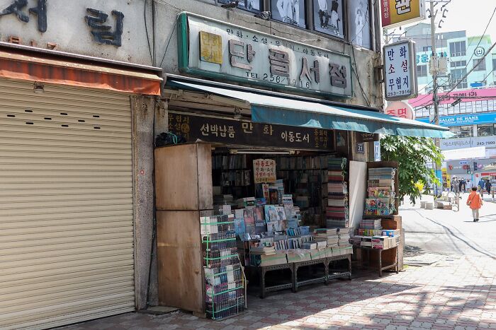 Small, cosy bookstore in a bustling street with shelves filled with books, showcasing a charming reading spot globally.