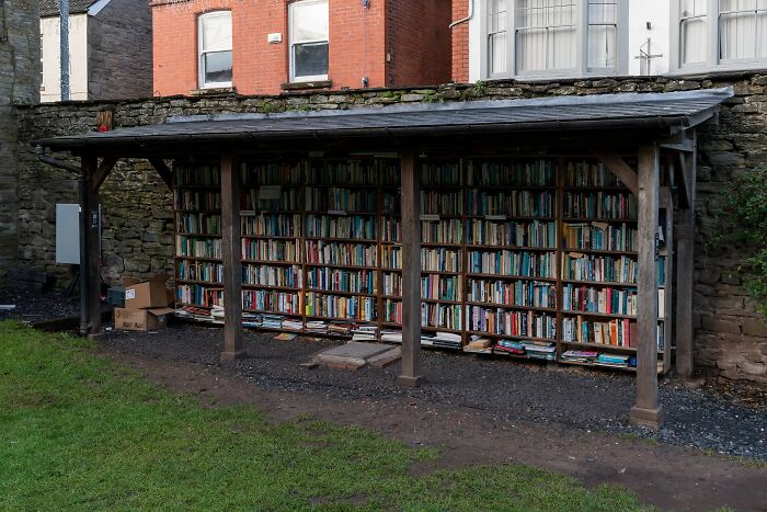 Outdoor wooden bookshelf filled with colorful books, part of stunning and impressive bookstores and libraries.