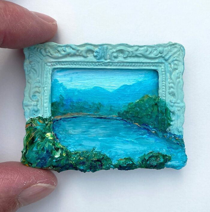 Small nature scene painting with sculpture elements in a detailed ornate frame held between fingers by Brooklyn artist.