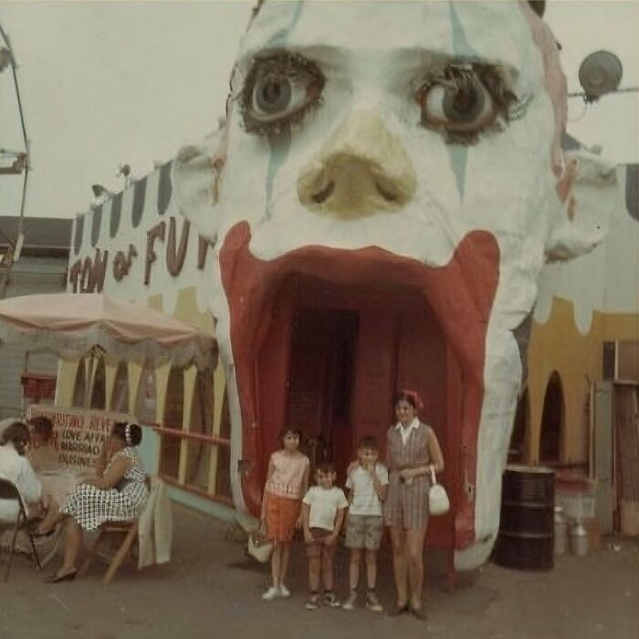 Niños y mujer posando frente a una atracción de parque con diseño de cabeza de payaso en imágenes malditas