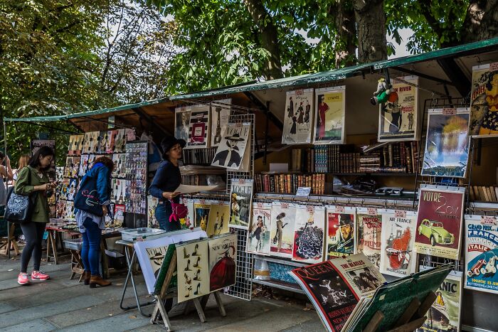 Outdoor bookstall with vintage posters and books, showcasing cosy and magical libraries and bookstores atmosphere worldwide.