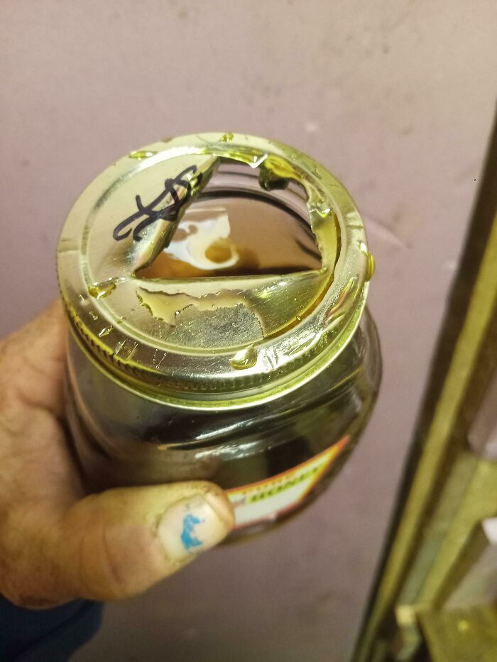 Hand holding a jar with a damaged broken lid, showing infuriating damage to borrowed belongings.