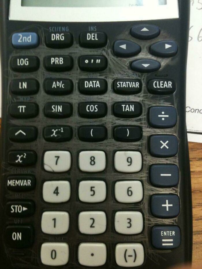 Calculator keypad scratched and damaged from use, showing signs of wear and tear on borrowed device.