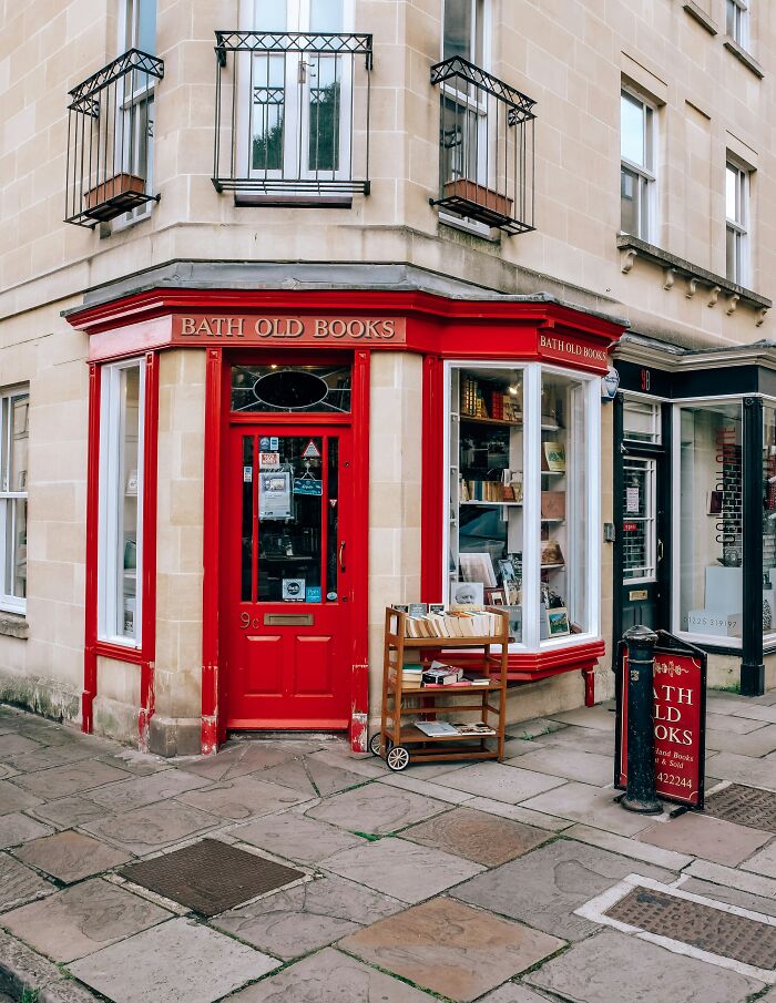Red exterior of Bath Old Books bookstore on a corner street, showcasing a vintage and impressive bookstore facade.