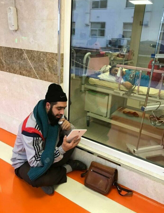 Teacher showing love for student by engaging through a tablet while the child rests in a hospital bed.