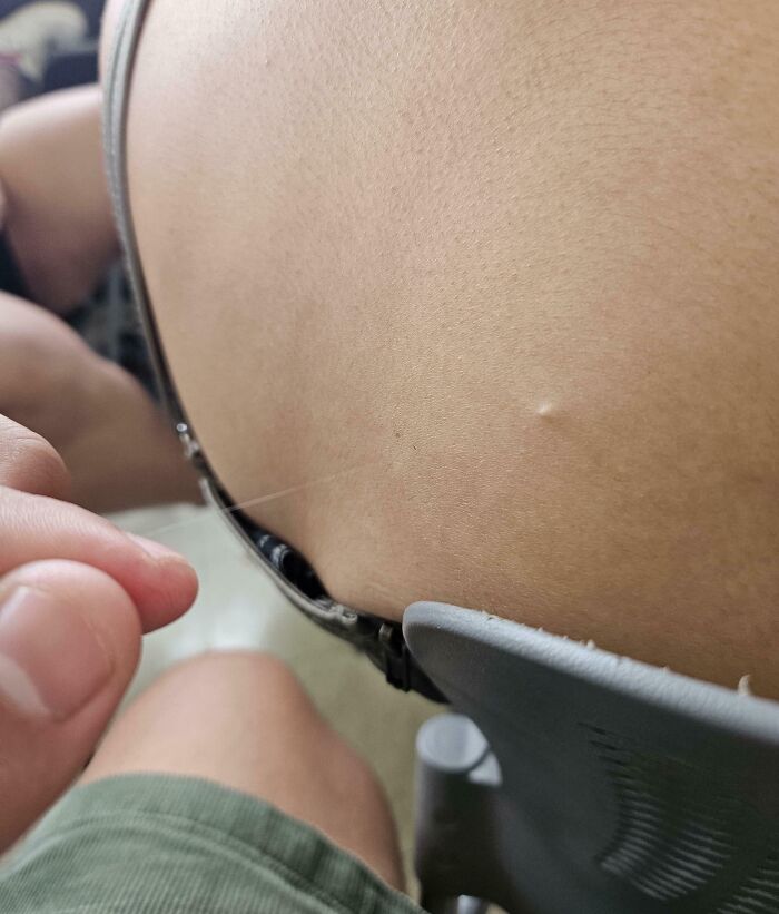 Close-up photo of human body skin showing a thin hair being pulled, highlighting bizarre and fascinating details.