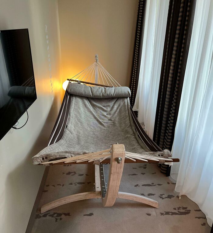 Hammock setup as a creative hotel design decision in a modern room with curtains and a wall-mounted TV.