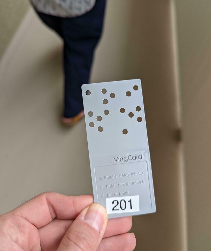 Hand holding a perforated card key with number 201 in a hotel, showcasing creative hotel design decisions.
