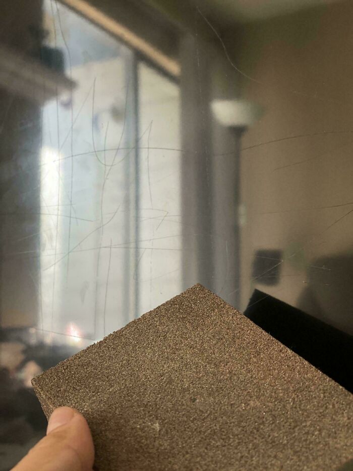 Close-up of a hand holding sandpaper against a scratched surface, highlighting unlucky parents’ struggles with damage repair.