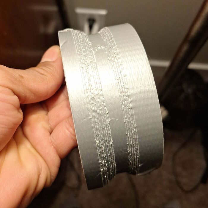 Cinta adhesiva mal cortada sostenida por una mano, ilustrando un momento frustrante para padres y madres.