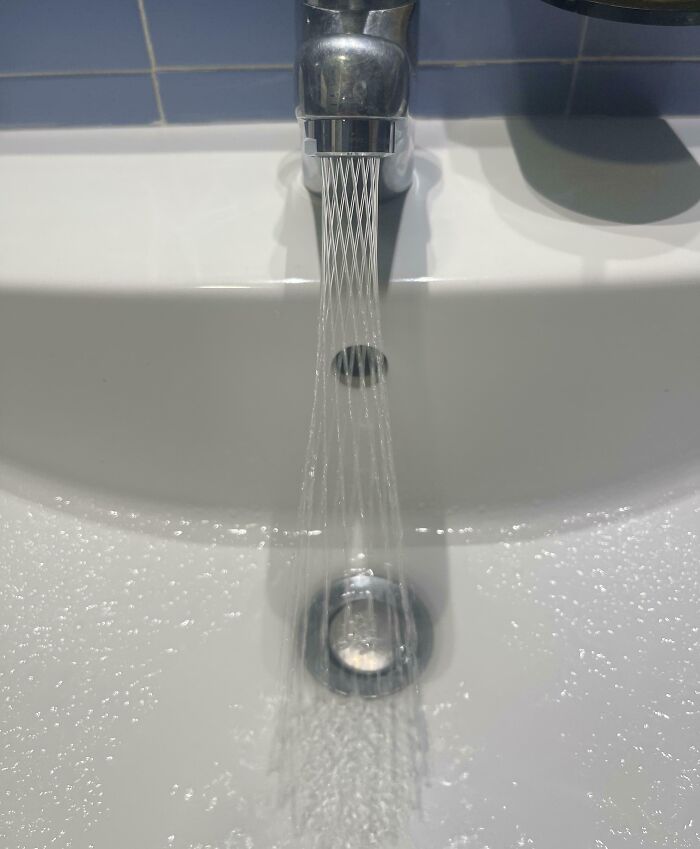 Modern hotel design decision featuring a sleek faucet with a unique fine stream water flow in a clean white sink.