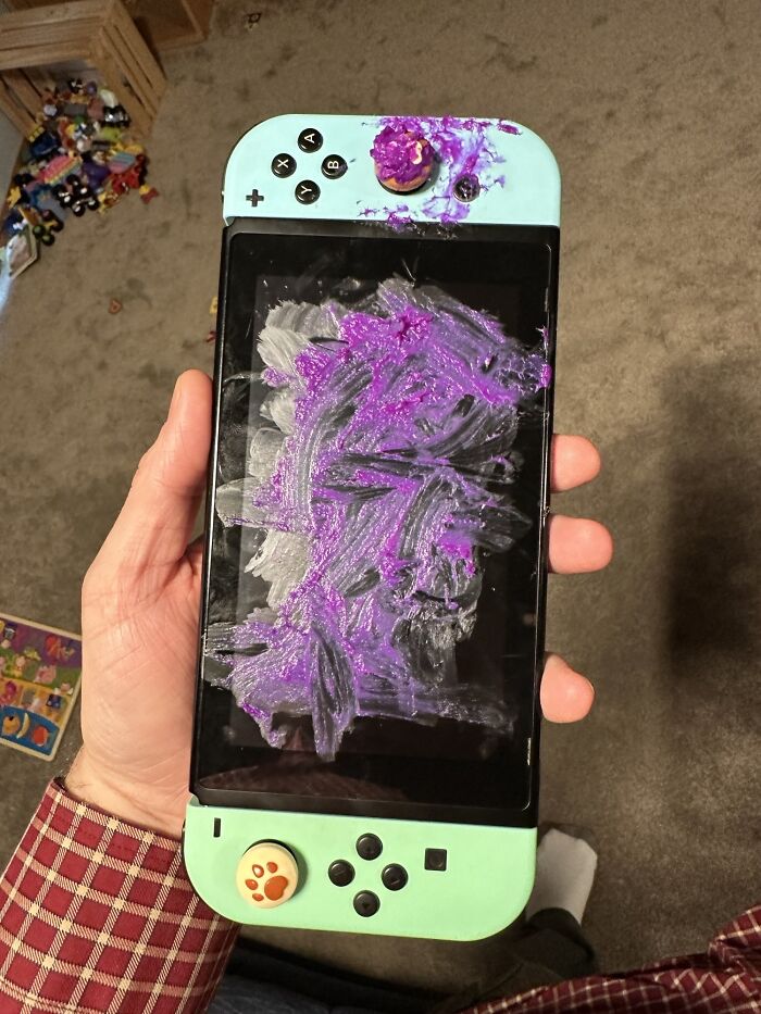 Control de videojuego manchado con pintura morada y blanca, ejemplo de padres teniendo un día peor que el tuyo.