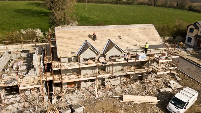 Partially built house surrounded by scaffolding with workers on site highlighting hidden costs of buying a home.