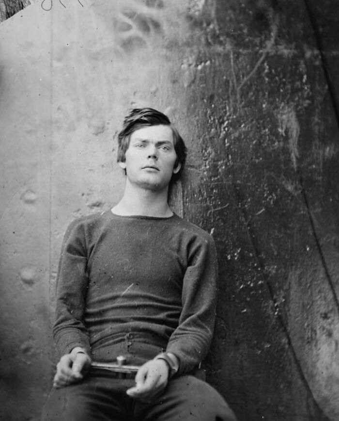 Young man from history sitting against a wall, showcasing handsome features among famous names from history.