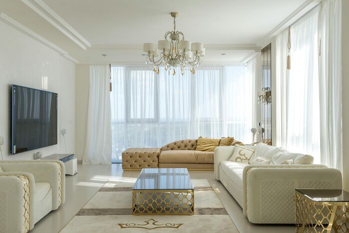 Bright modern living room with white sofas and gold accents illustrating hidden costs of buying a home.