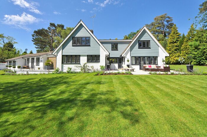 Large modern home with well-maintained lawn under a blue sky illustrating hidden costs of buying a home.