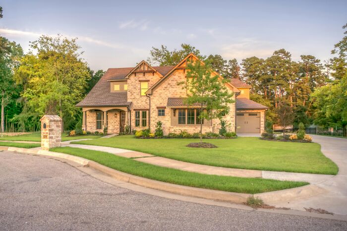 Modern two-story brick home with well-maintained lawn and driveway, illustrating hidden costs of buying a home.