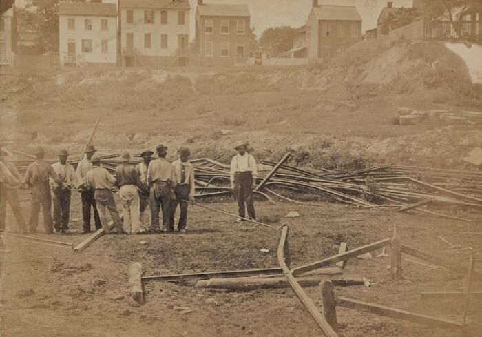Group of vintage American working class men gathered at a construction site, engaged in their jobs outdoors.