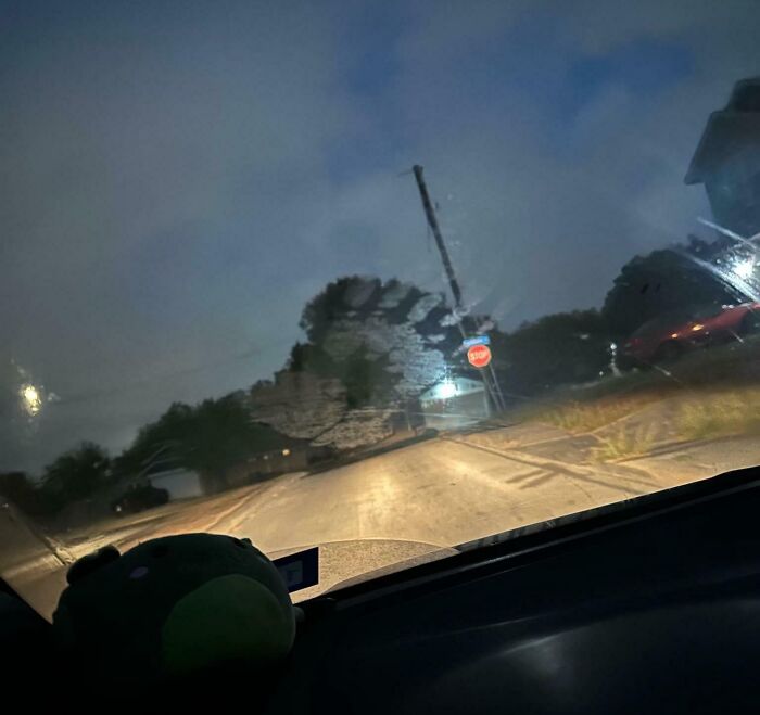 View through a car windshield at night showing a ghostly handprint and a stop sign on a dimly lit street in a chilling ghost encounter.