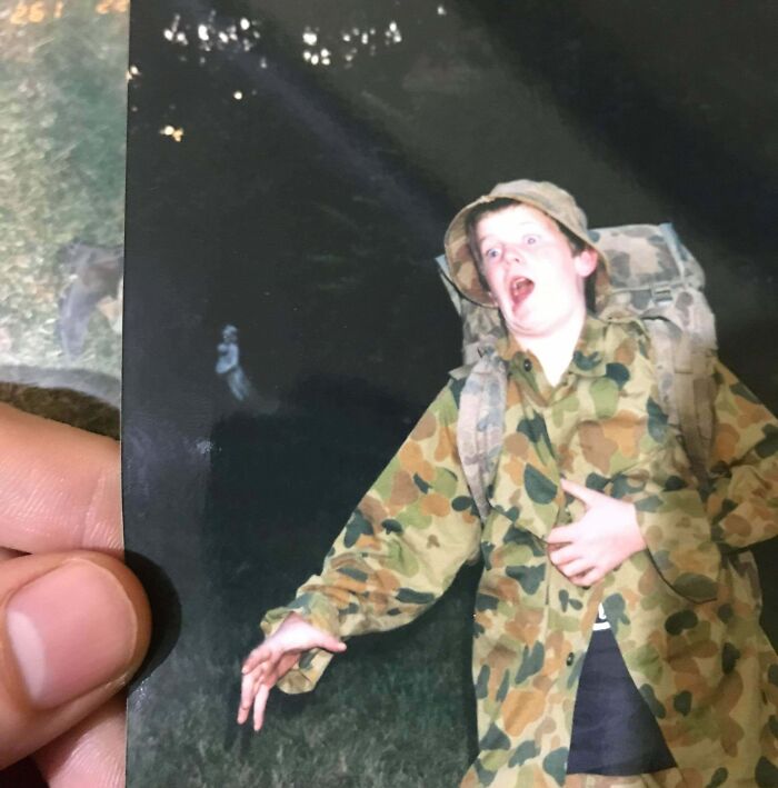 Person in camo jacket and hat with shocked expression, appearing to encounter chilling ghost in a dark outdoor setting.