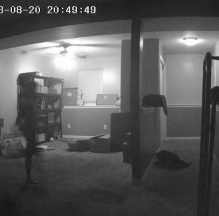 Black and white security camera image showing a faint ghostly figure in a dimly lit room, capturing a chilling ghost encounter.