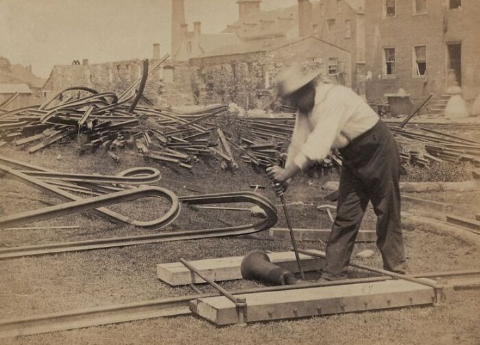 Vintage photo of an American working class man in the middle of his job with industrial tools and metal parts outdoors.