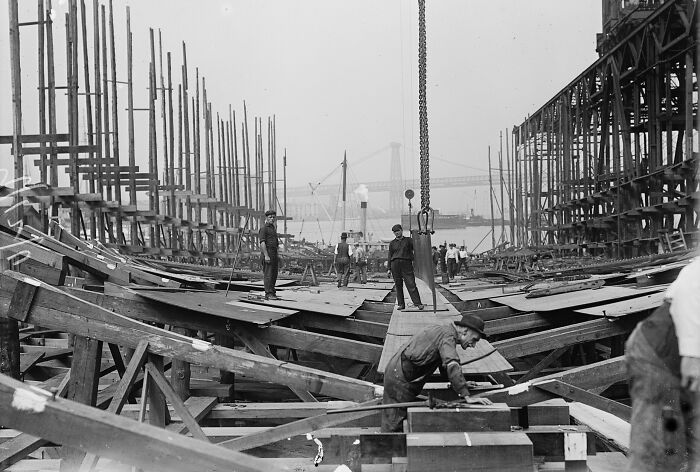 Vintage photo of American working class people constructing a large wooden structure at an early 20th century job site.