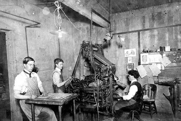 Three American working class people operating machinery and preparing materials in a vintage industrial workspace.