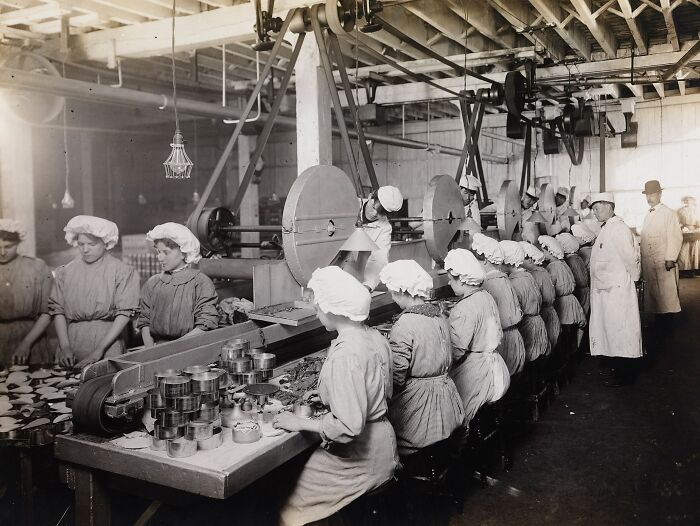 Vintage photo of American working class women in a factory assembly line performing manual tasks during their jobs.