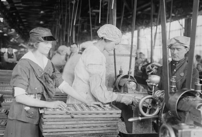 Vintage photo showing American working class people operating industrial machinery in a factory setting during their jobs.