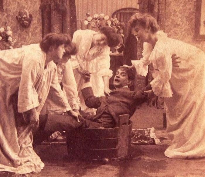 Victorian era scene showing women helping a man inside a wooden tub, capturing strange moments from Victorian times.