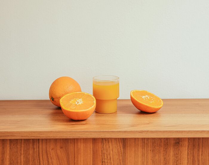 Fresh oranges and a glass of orange juice on a wooden table, illustrating common foods that go bad quickly.