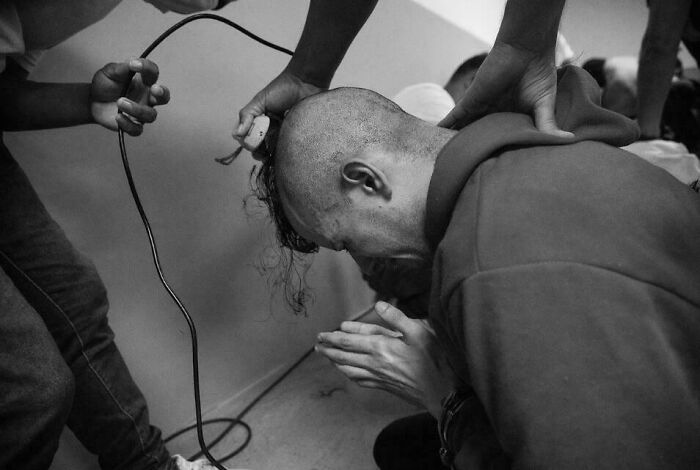 Andry Romero, un maquillador gay enviado a El Salvador, solloza y reza mientras los guardias le afeitan la cabeza.