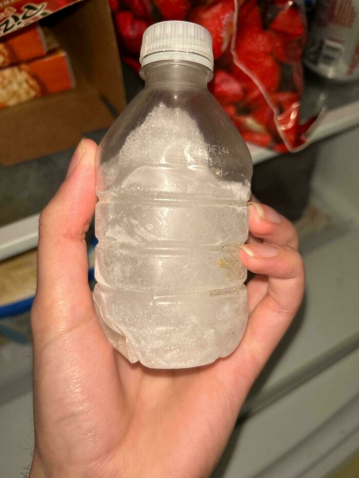 Hand holding a frozen water bottle demonstrating a practical travel hack for staying hydrated on the go.
