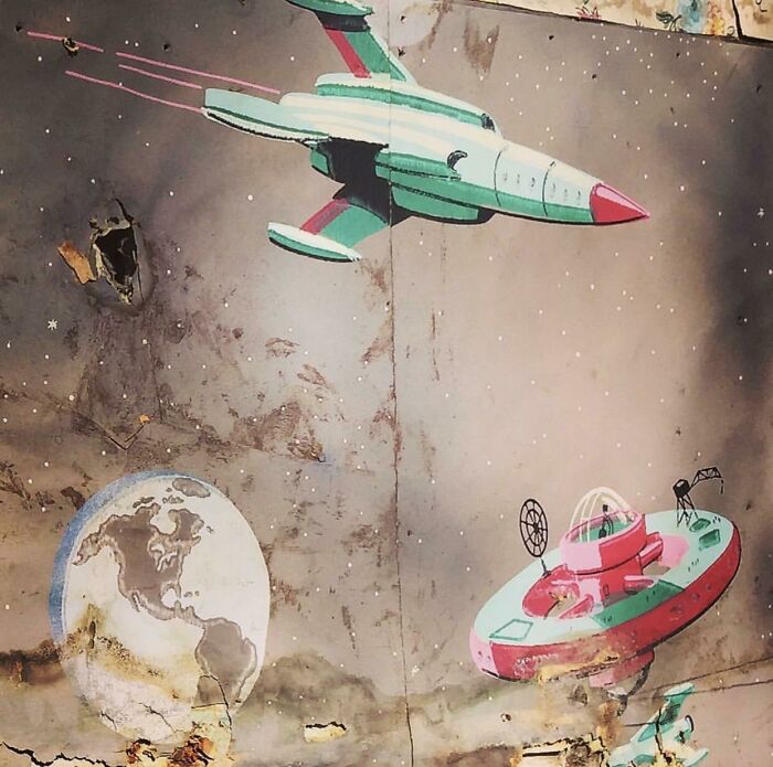 Retro space mural with rockets and Earth, found hidden and forgotten inside an old house wall.
