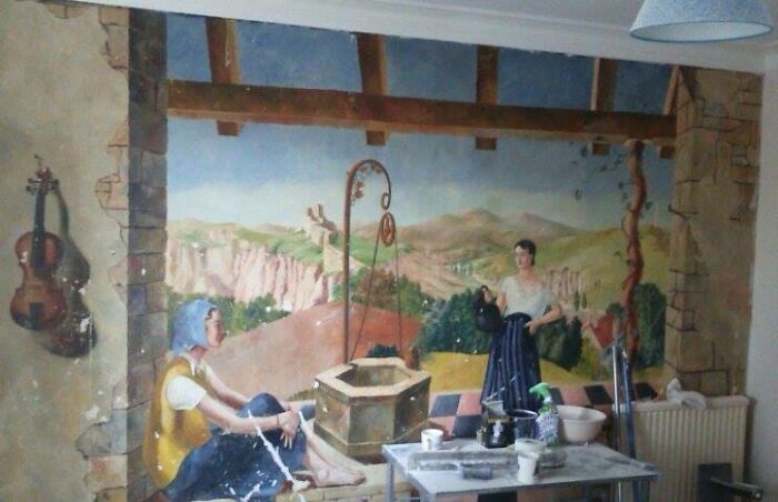Mural of people near a well painted on an old house wall, part of cool things found buried and forgotten.