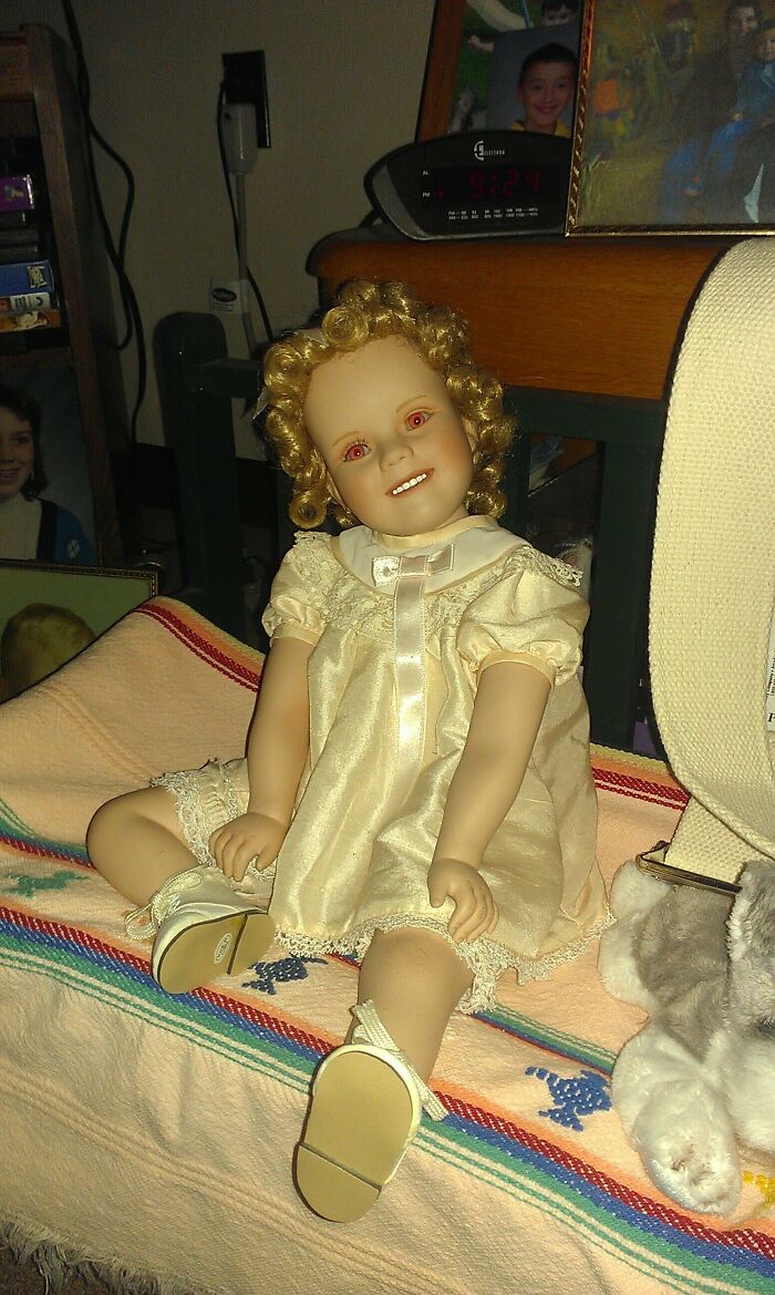 Old porcelain doll with curly hair and vintage dress found hidden in an old house among forgotten items