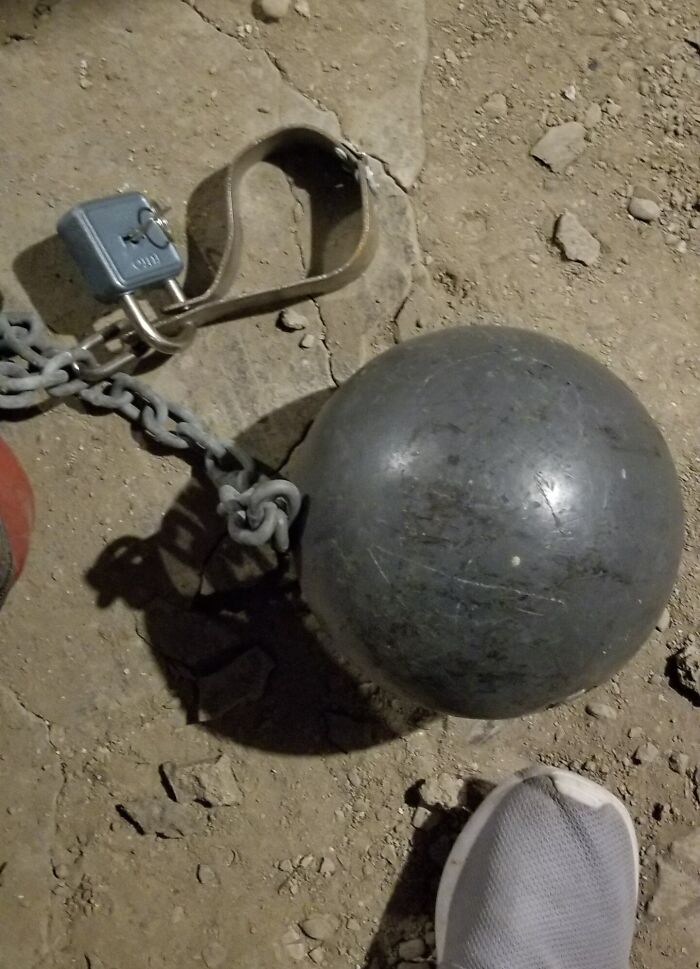 Ball and chain found buried in an old house on a dirt floor next to a sneaker, a hidden forgotten item discovery
