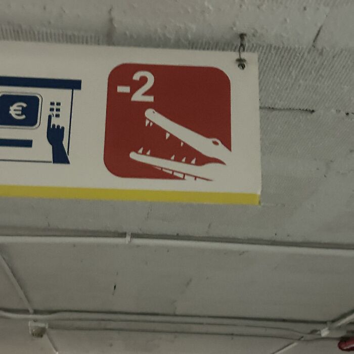 Parking sign with a red panel depicting a crocodile head and the number -2, creating a funny and confusing visual.