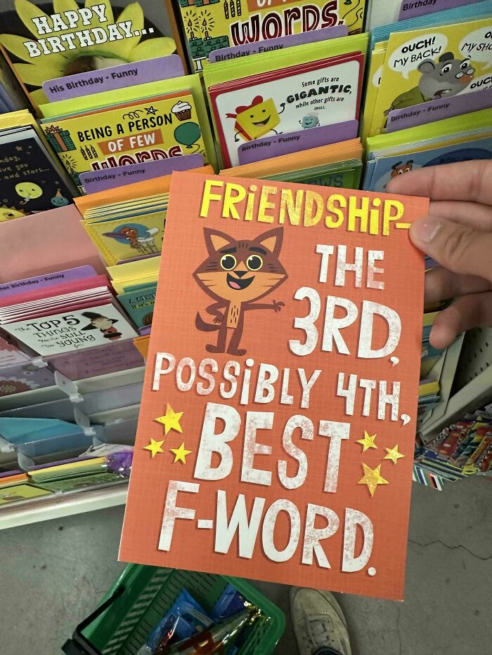 Hand holding a funny birthday card about friendship, surrounded by humorous cards, capturing confused moments.