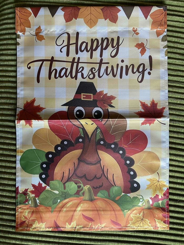 Funny pic of a Thanksgiving flag with a turkey and pumpkins, showing a humorous misspelling on a fall-themed decoration.