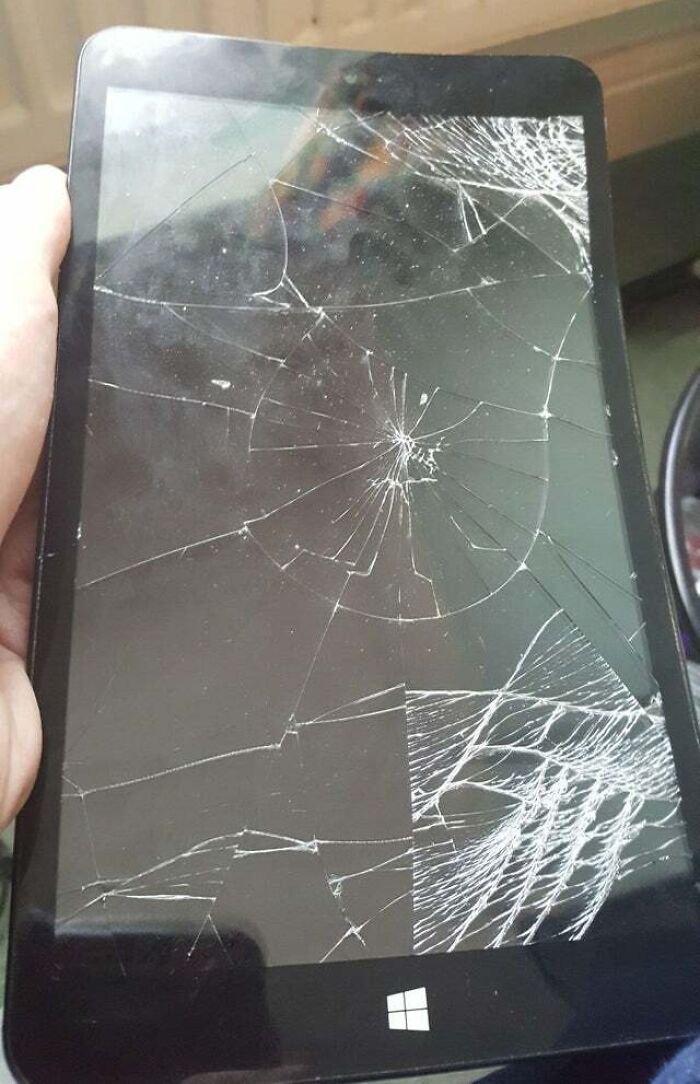 Shattered tablet screen held in hand, showing severe damage, illustrating people damaging things they borrowed.