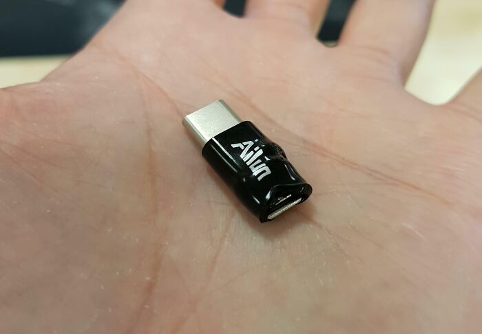Damaged USB adapter resting on a hand, showcasing a common example of people damaging things they borrowed.