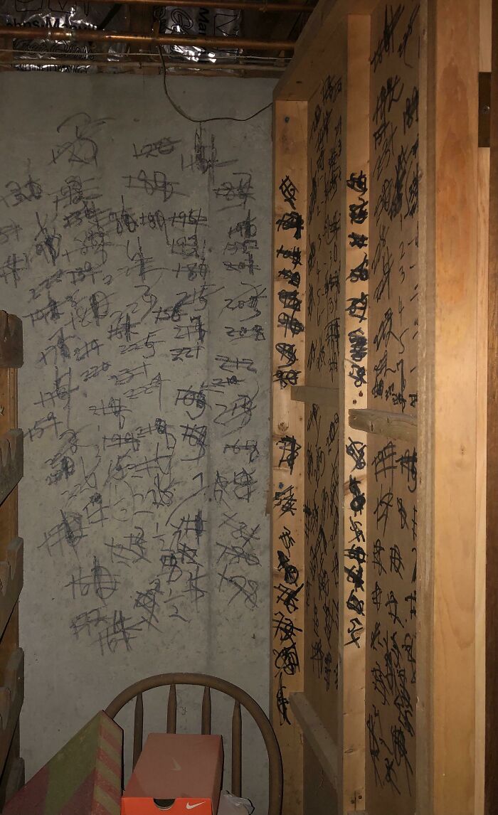 Confusing wall and wooden panel covered in numerous black scribbles and markings in a small cluttered room.