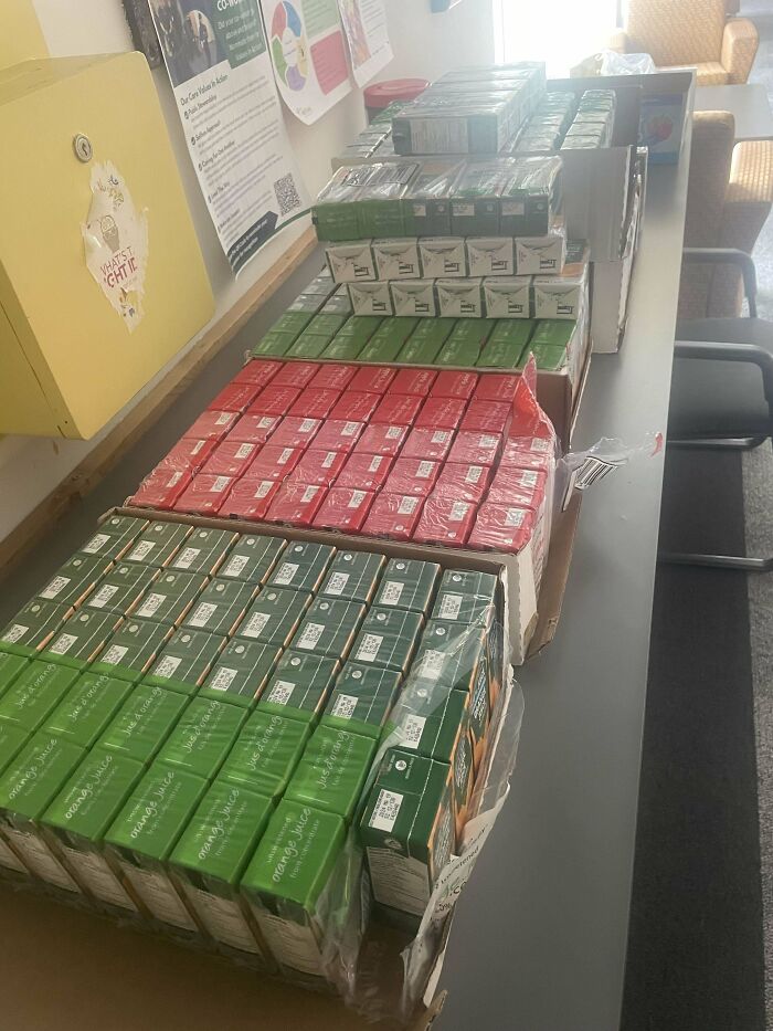 Stacks of boxed drinks on a table in a cluttered room, depicting an extremely toxic work environment scene.