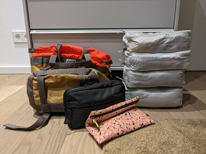 Packed travel bags and organizers neatly arranged on a wooden floor showcasing practical travel hacks for efficient packing.