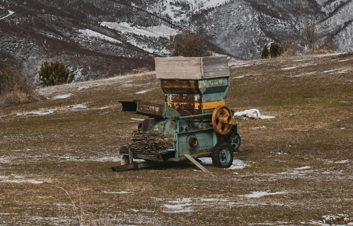 Old rusted machine abandoned in a snowy mountainous field, evoking unsettling and scary vibes from distant locations.