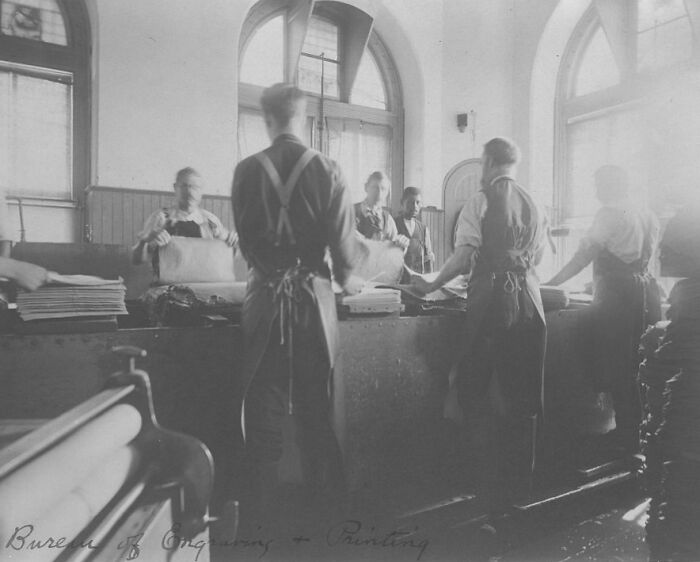 Vintage photo of American working class people handling paper and printing materials in a factory setting.