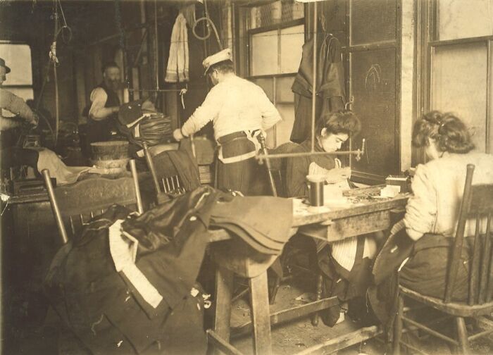 Vintage photo of American working class people sewing and tailoring clothes in a workshop setting.